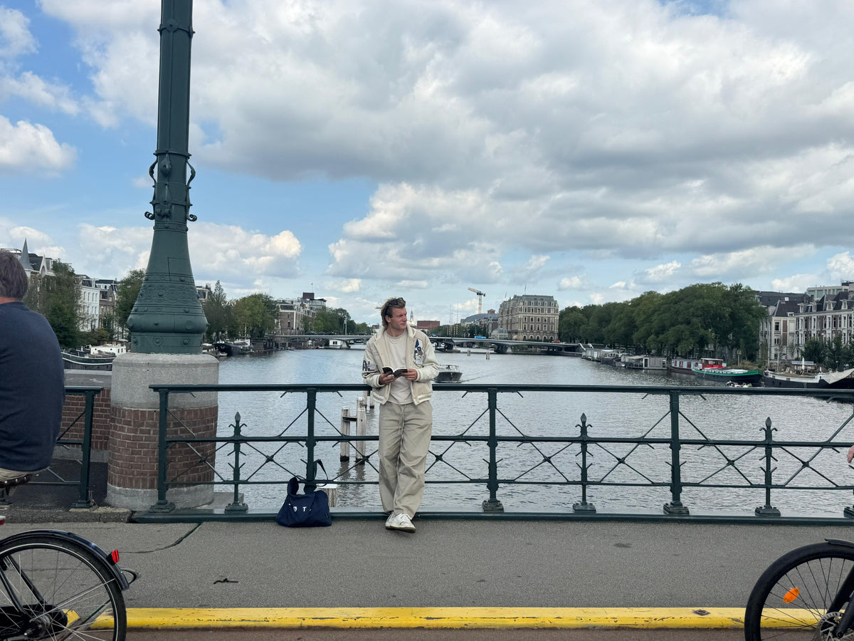Leaning on the bridge railing with a book instead of a phone