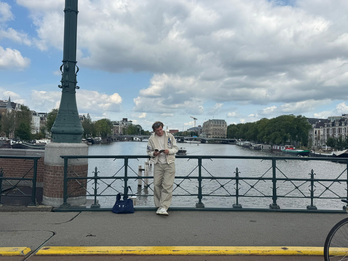 Standing still on the bridge with a book, the city carrying on behind