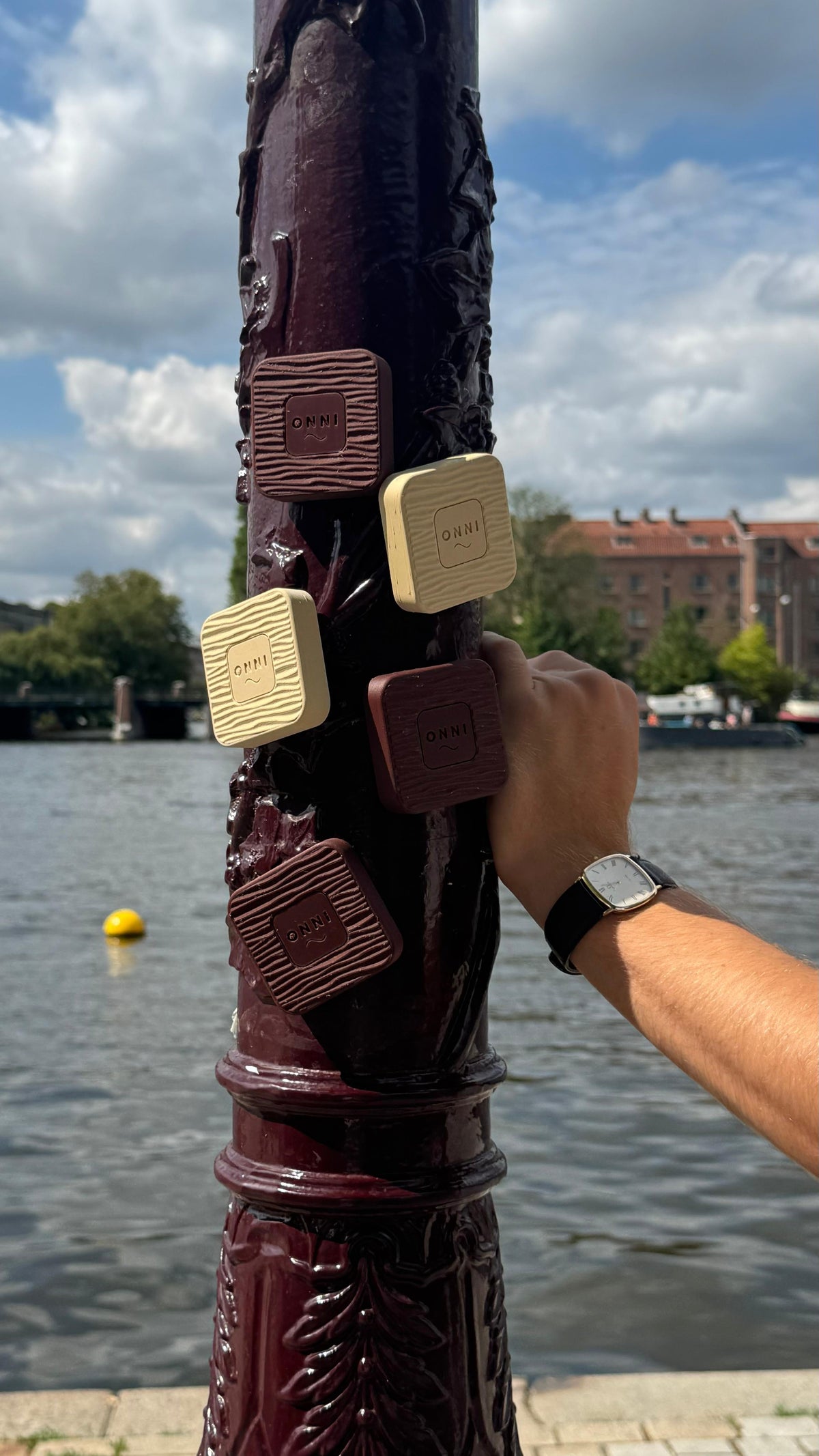 Five Kiuas blocks clinging to a lamppost by the water, magnets holding fast