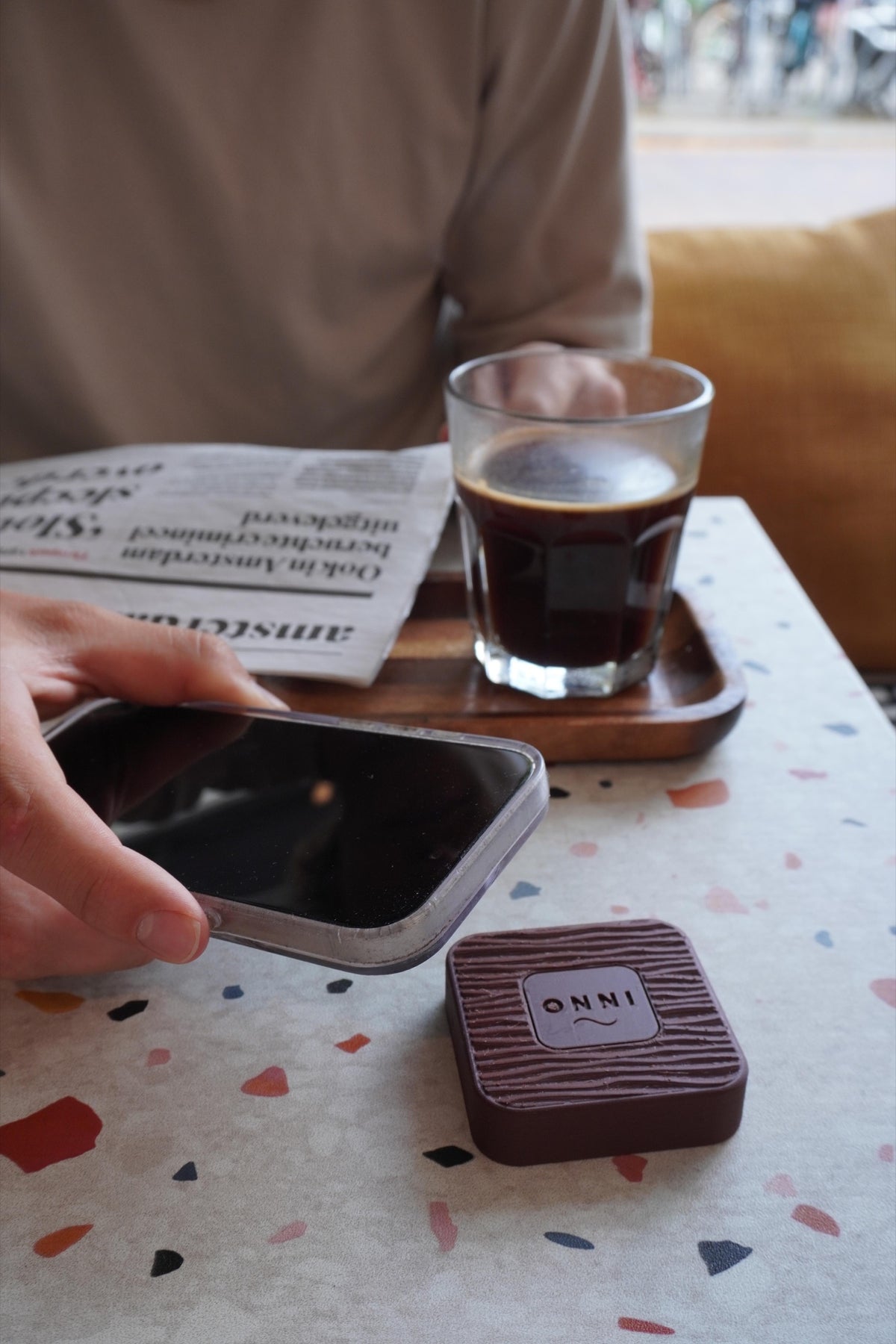 An iPhone held above a Walnut Kiuas on a café table, showing the scan gesture